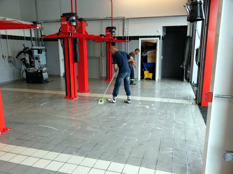 Two Rodal operatives applying an anti-slip treatment to a tiled workshop floor